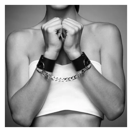Manchettes de bondage larges noires en cuir végétalien, marque Bijoux Maze, double usage bracelet et menotte avec chaîne.