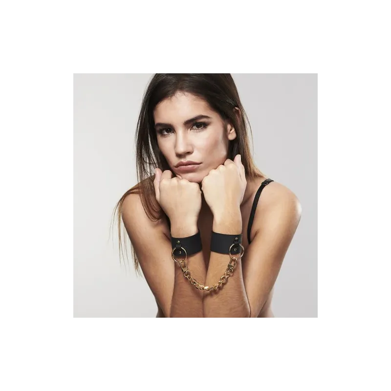 Wide black bondage cuffs in vegan leather by Bijoux Maze, dual use as bracelet and handcuffs with chain.